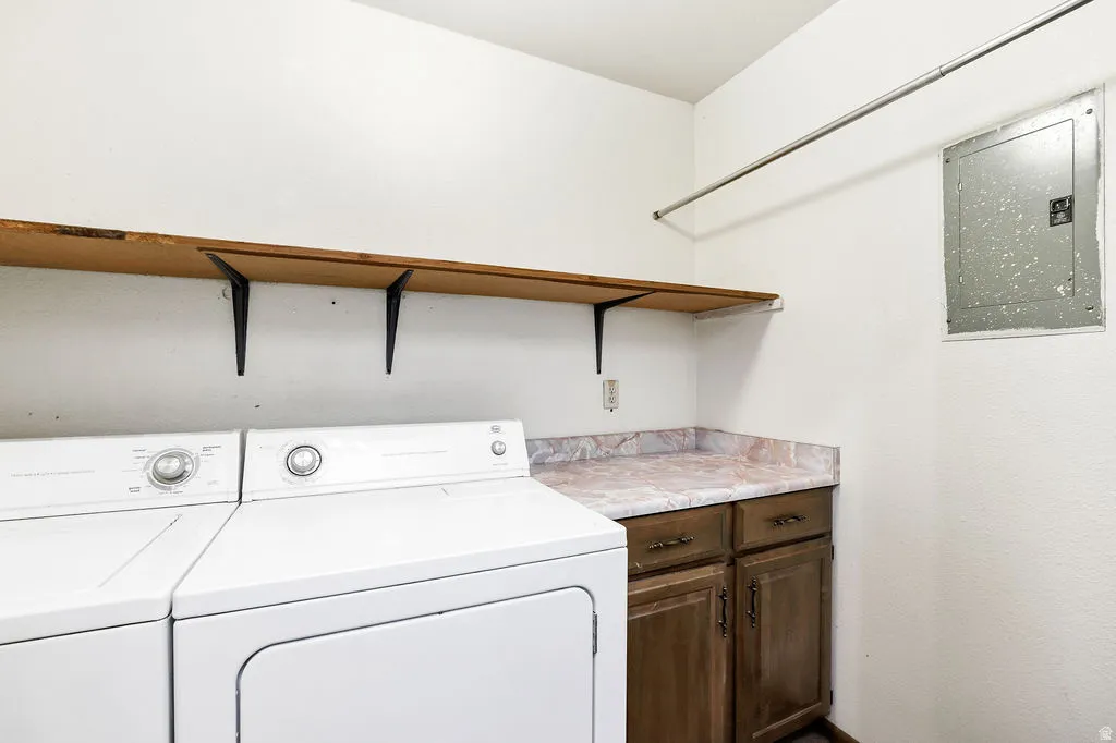 Dedicated laundry area featuring a wood-finish shelf, hanging rod, wood-finish cabinetry, and a marbled countertop