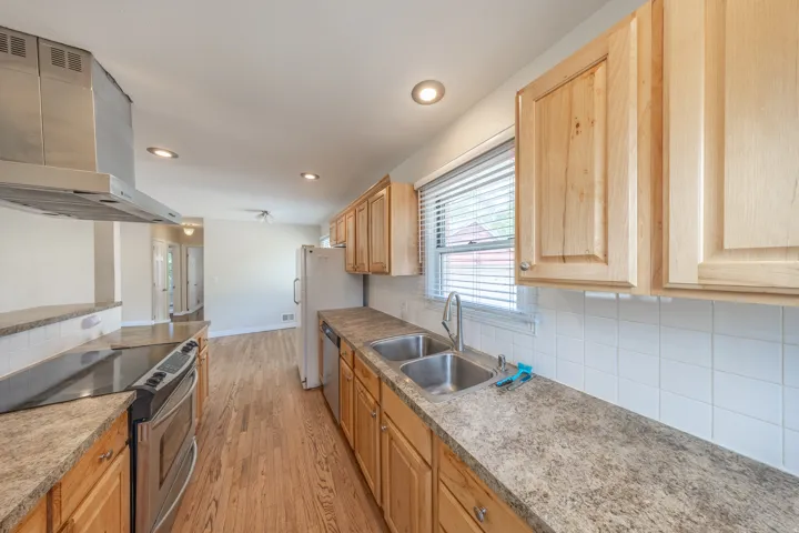 Galley kitchen featuring wood-finish cabinetry, stainless steel appliances, and abundant counter space