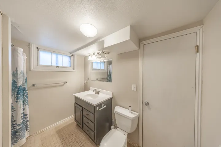 Bathroom featuring a dark wood-finish vanity with a white countertop and integrated sink, a mirrored medicine cabinet, and a multi-bulb vanity light fixture