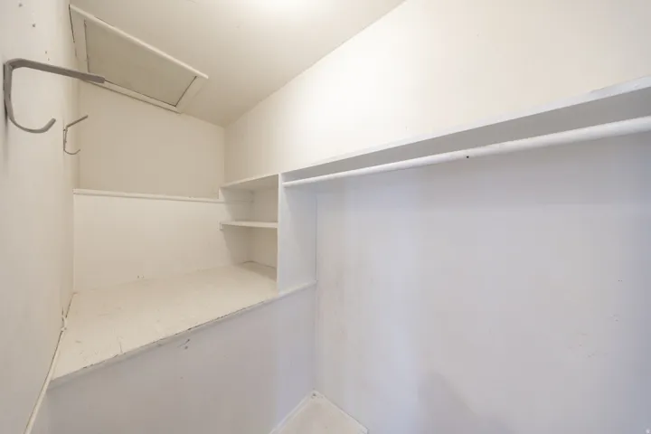 Interior storage space featuring built-in shelving, a hanging rod, and wall-mounted hooks