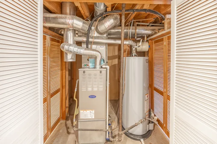 Utility closet featuring a furnace and water heater installation