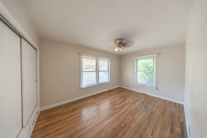 Spacious room featuring wood-finish flooring, light-toned walls, and multiple windows with blinds
