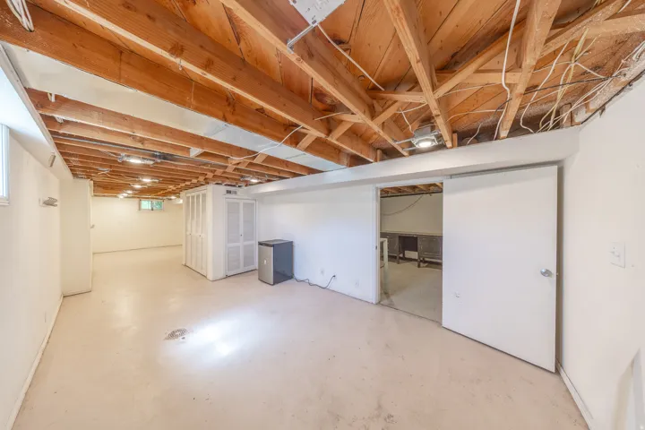 Expansive unfinished basement featuring an exposed wood joist ceiling, painted concrete flooring, and recessed lighting