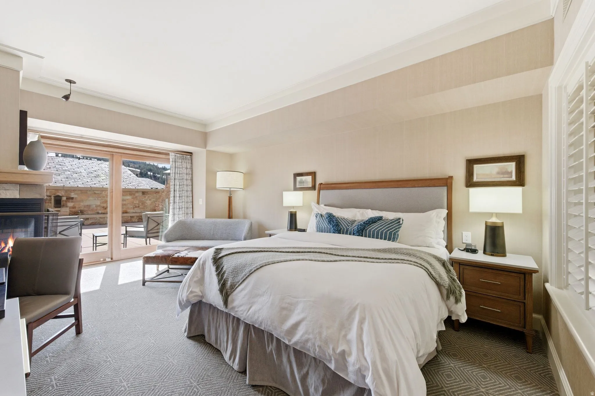 Spacious room featuring patterned carpeting, a stone fireplace, and double glass doors leading to an outdoor patio