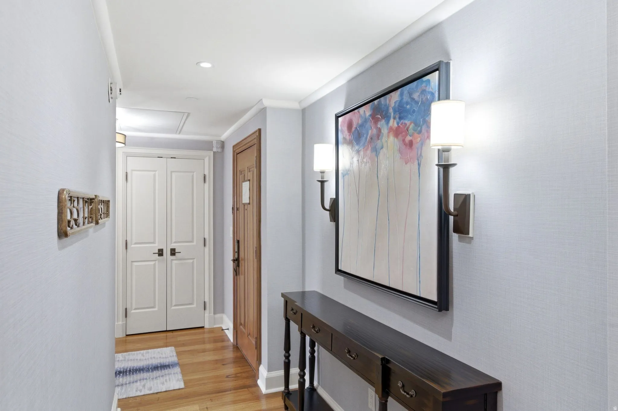 Hallway featuring wood-finish flooring, light blue textured wallpaper, and recessed ceiling lighting