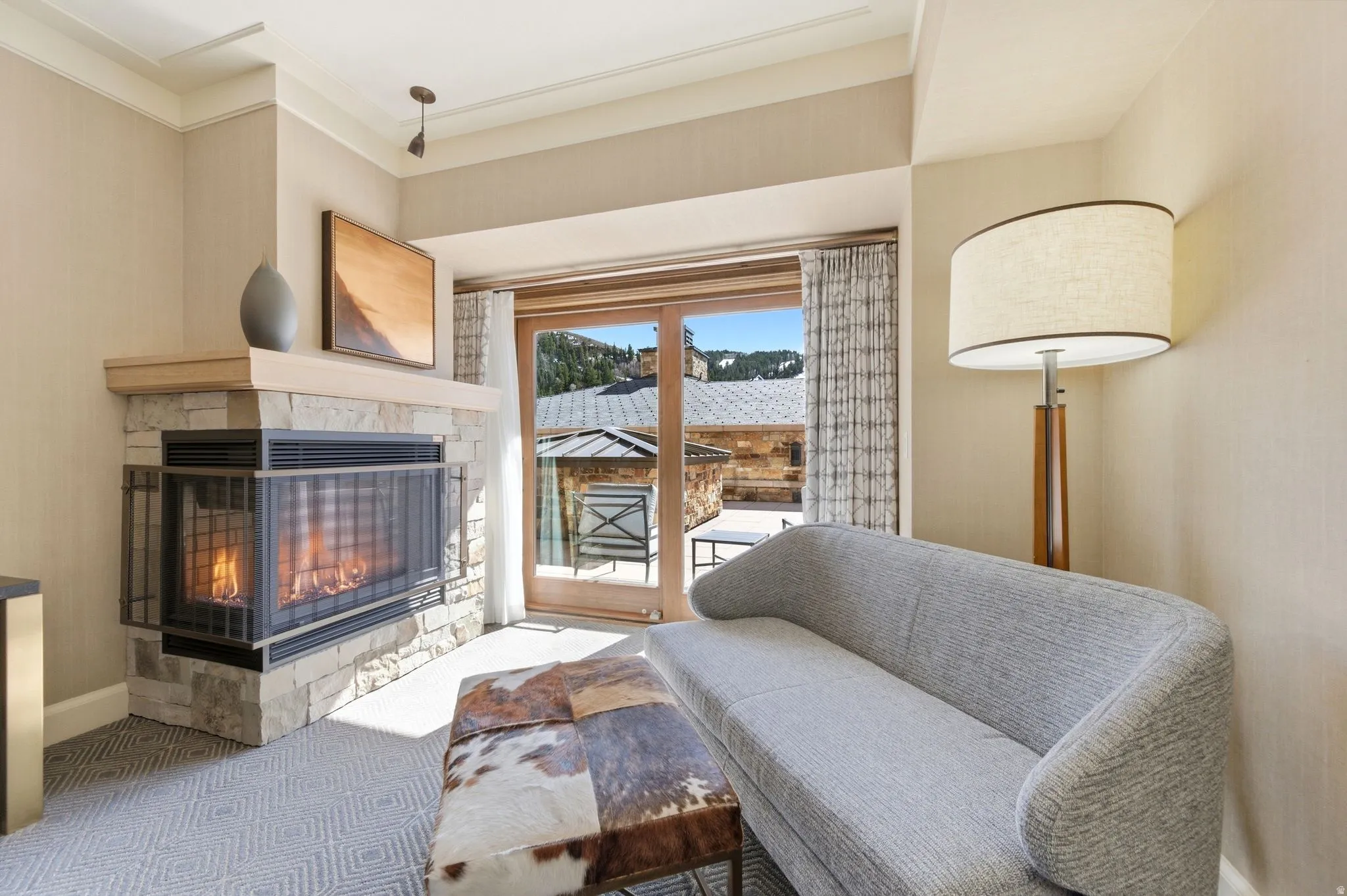 Stone-clad fireplace with a light-toned wood mantel and integrated fire screen