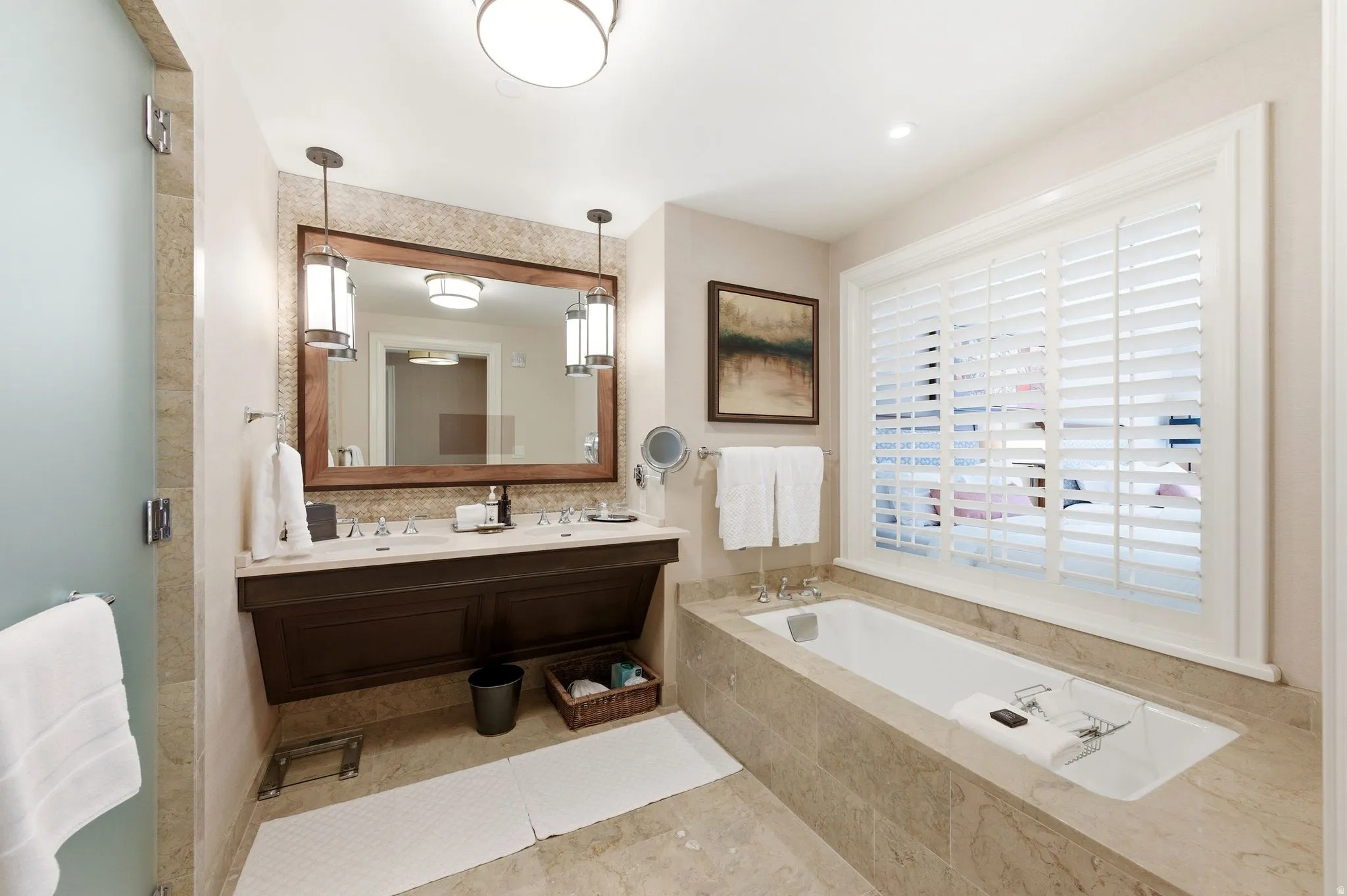 Bathroom featuring a built-in soaking tub, plantation shutters, and a double vanity with undermount sinks