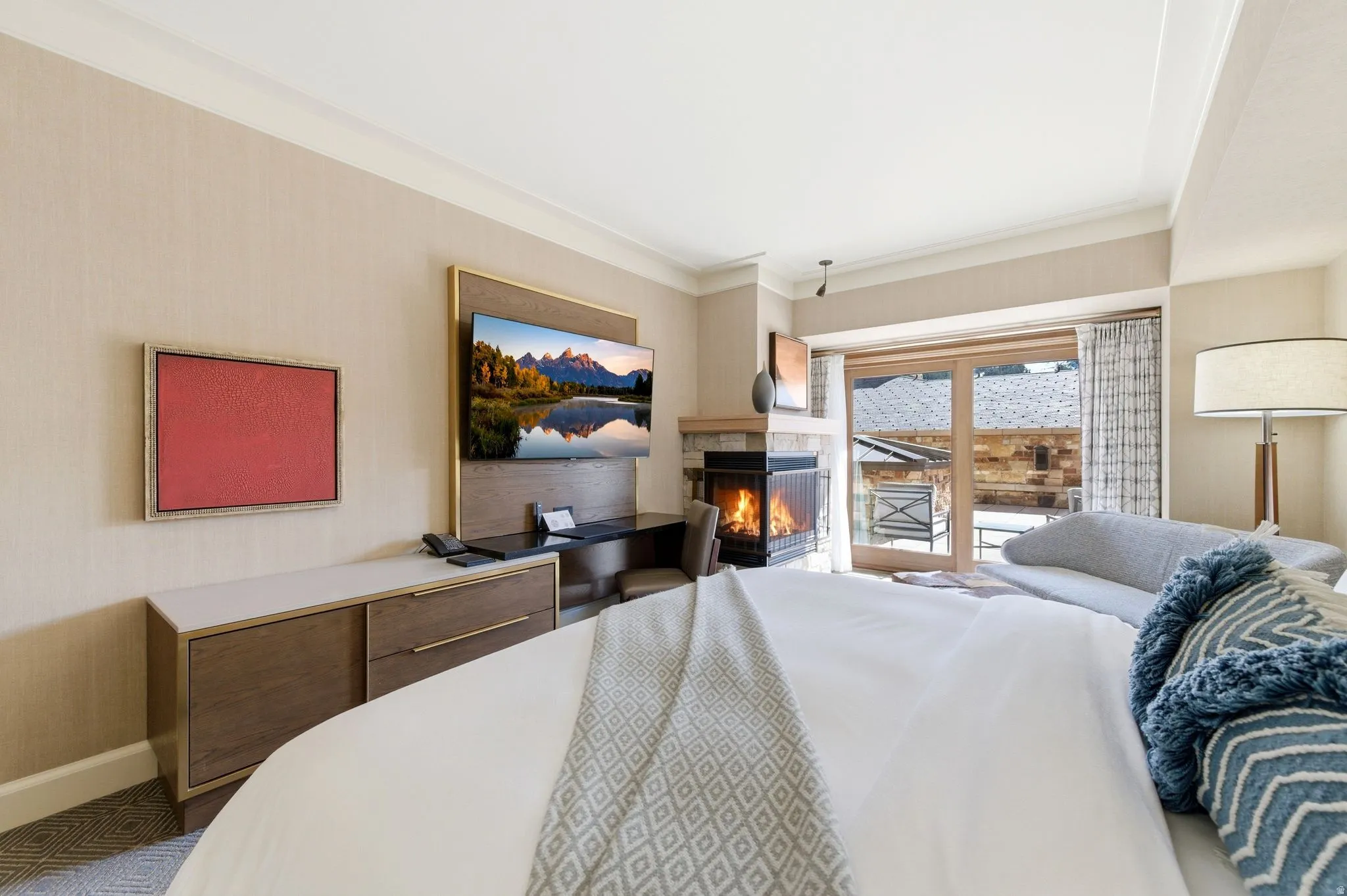 Bedroom featuring a gas fireplace with stone surround, wood-finish flooring, and direct access to an outdoor patio through glass sliding doors