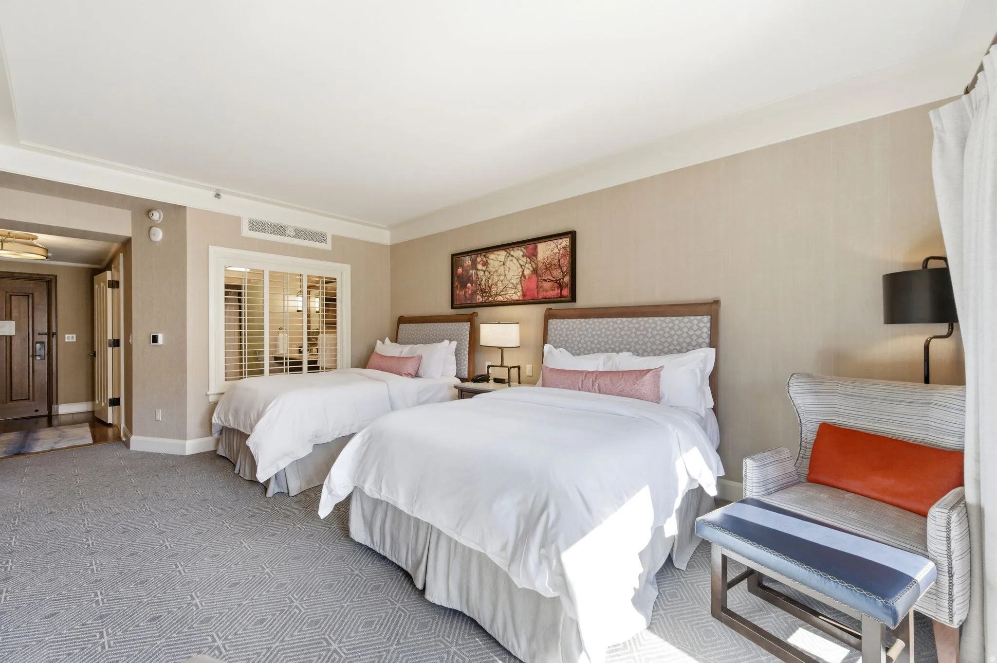 Two beds featuring patterned headboards and crisp white bedding