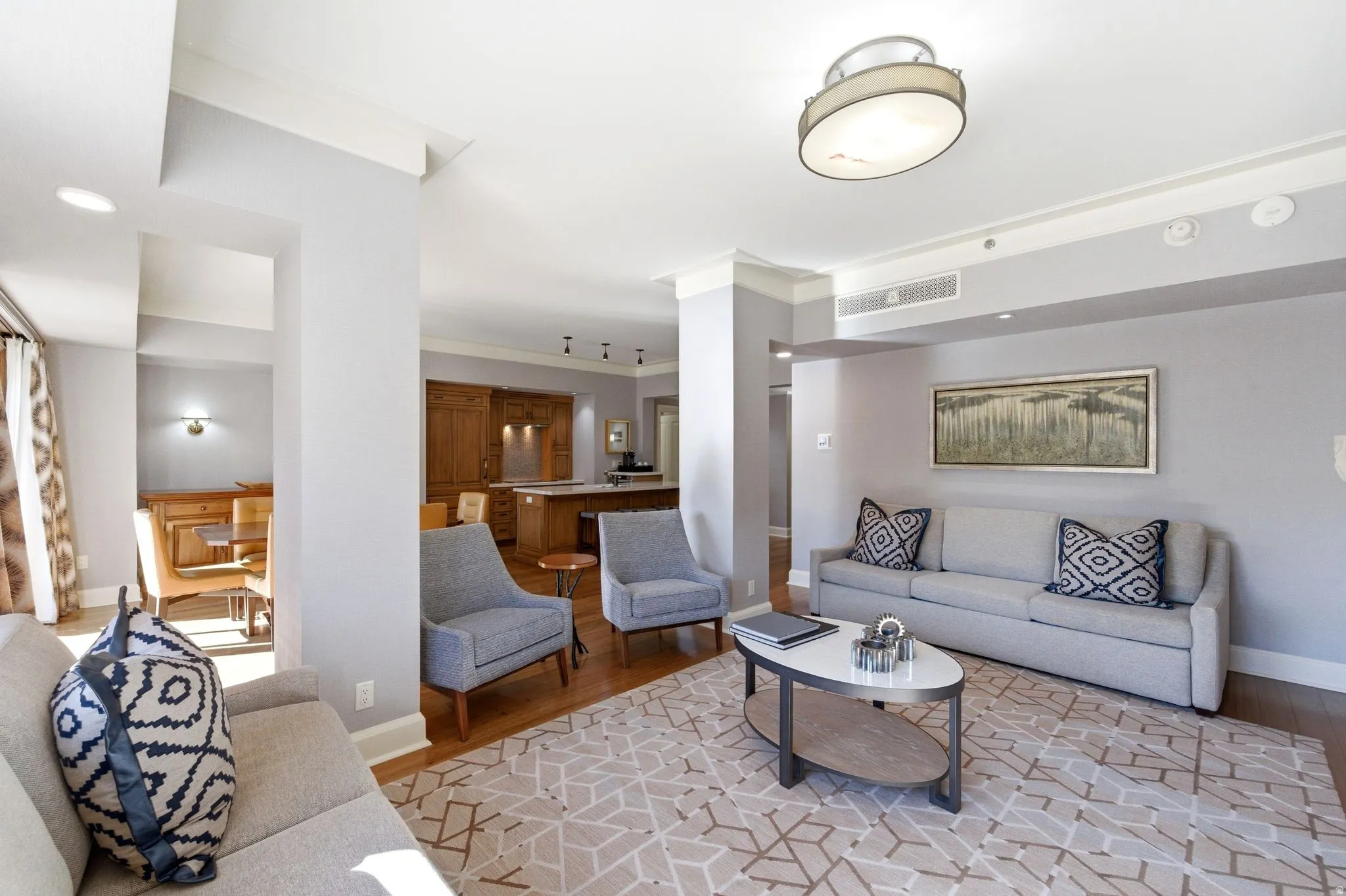 Spacious living area featuring light-colored walls, crown molding, and wood-finish flooring