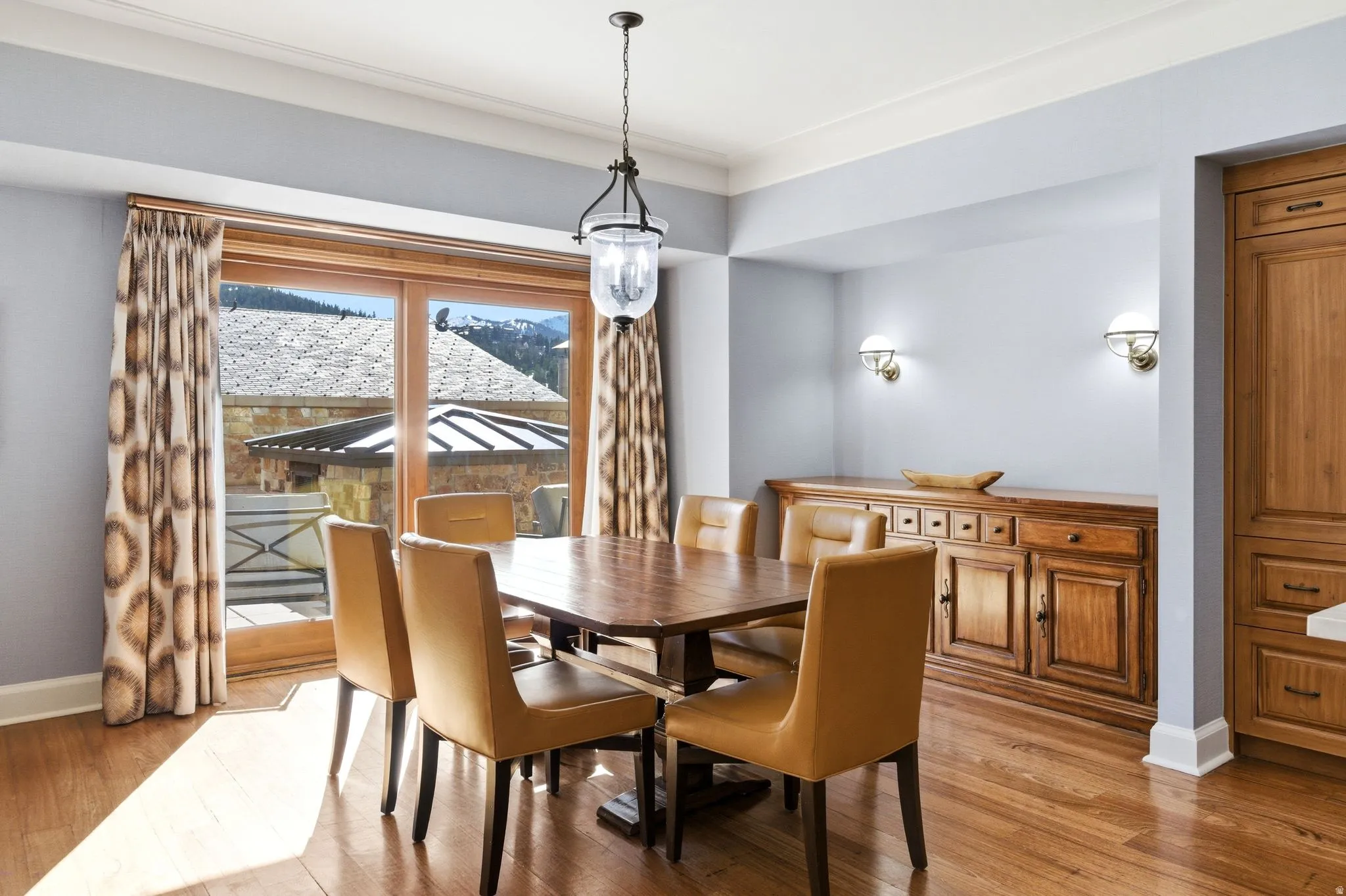 Spacious room featuring wood-finish flooring, a contemporary chandelier, two wall sconces, and light blue walls