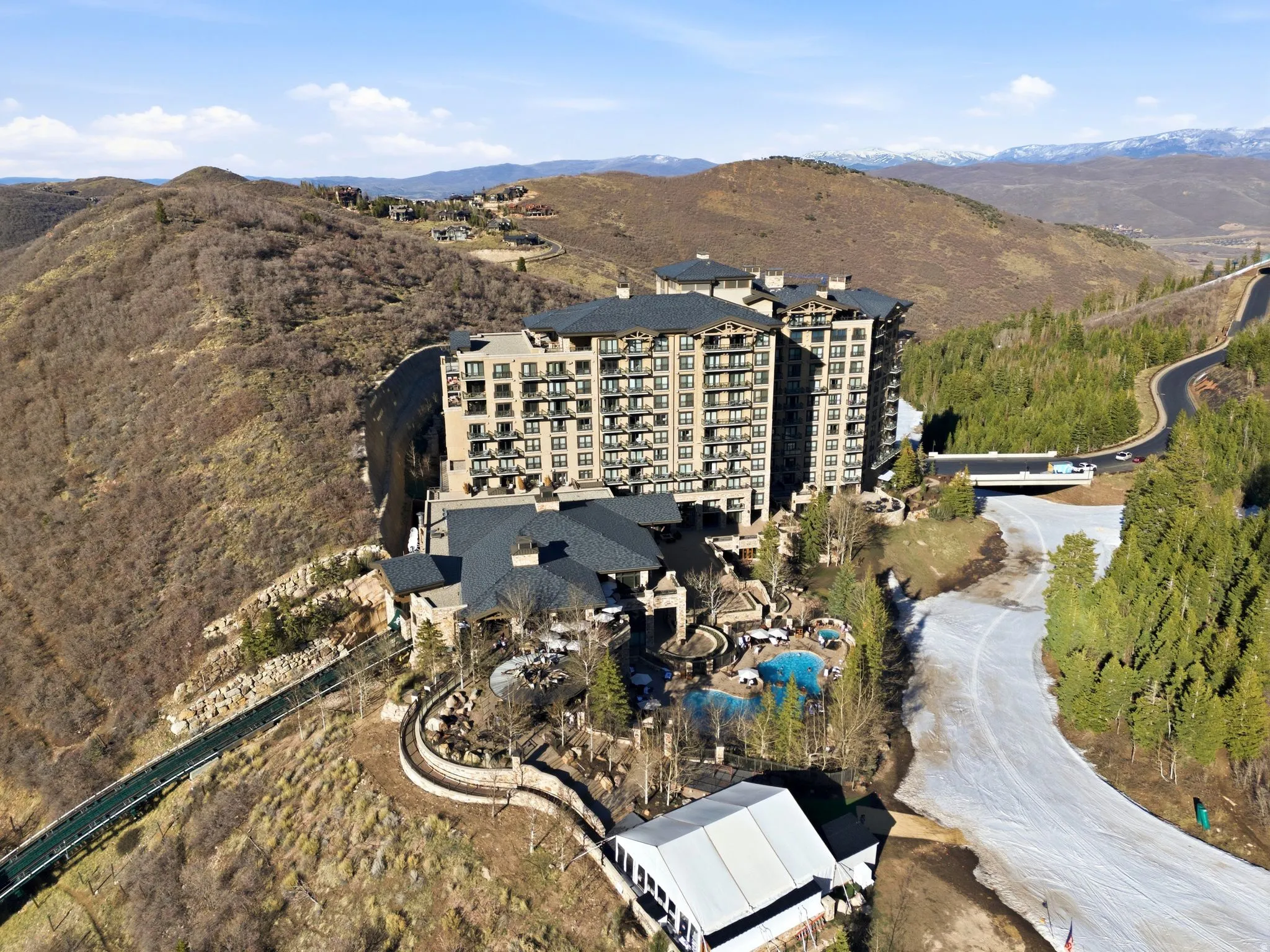 Multi-story building featuring numerous balconies, a sloped shingle roof, and exterior accent lighting