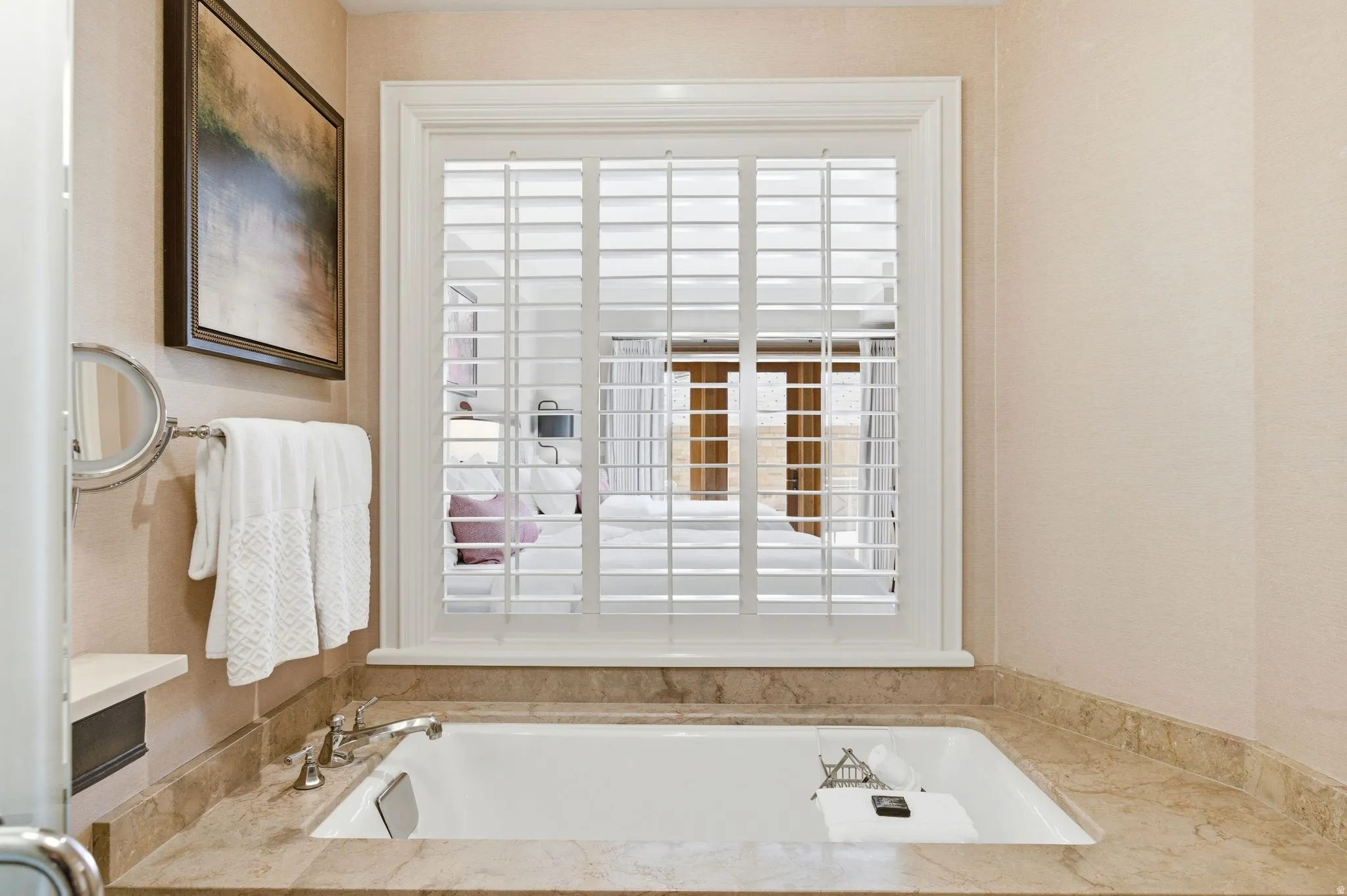 Built-in soaking tub featuring a stone-look surround and deck-mounted fixtures