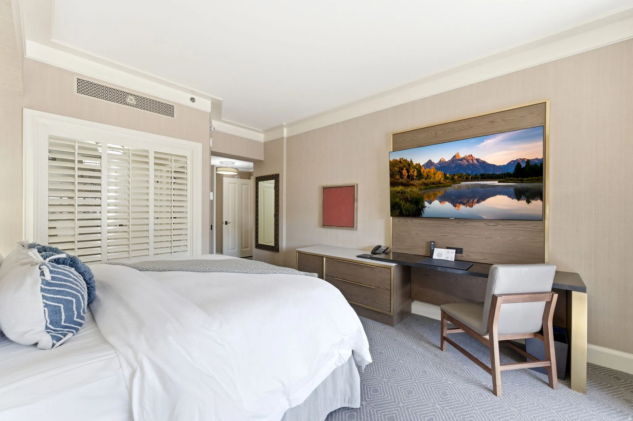 Bedroom featuring white plantation shutters, crown molding, and textured wall coverings