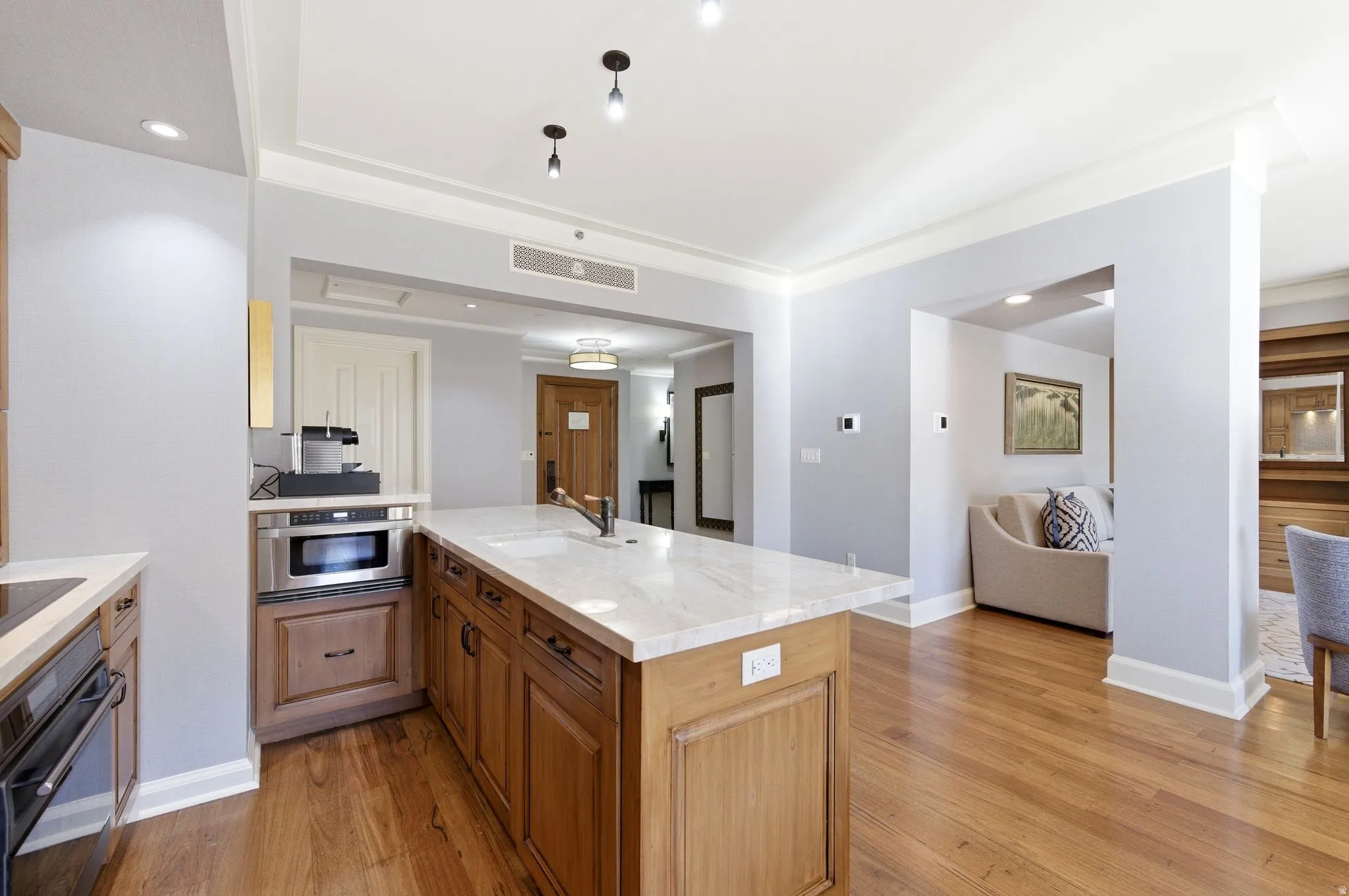 Kitchen island featuring a white stone countertop with an undermount sink and dark fixtures