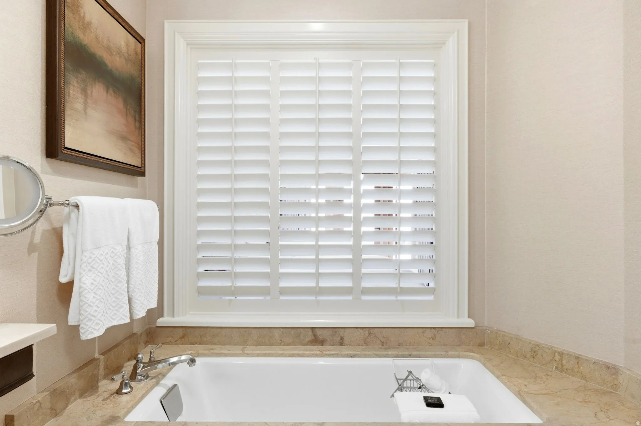 Built-in soaking tub with a polished chrome deck-mounted faucet, surrounded by a natural stone countertop and matching backsplash