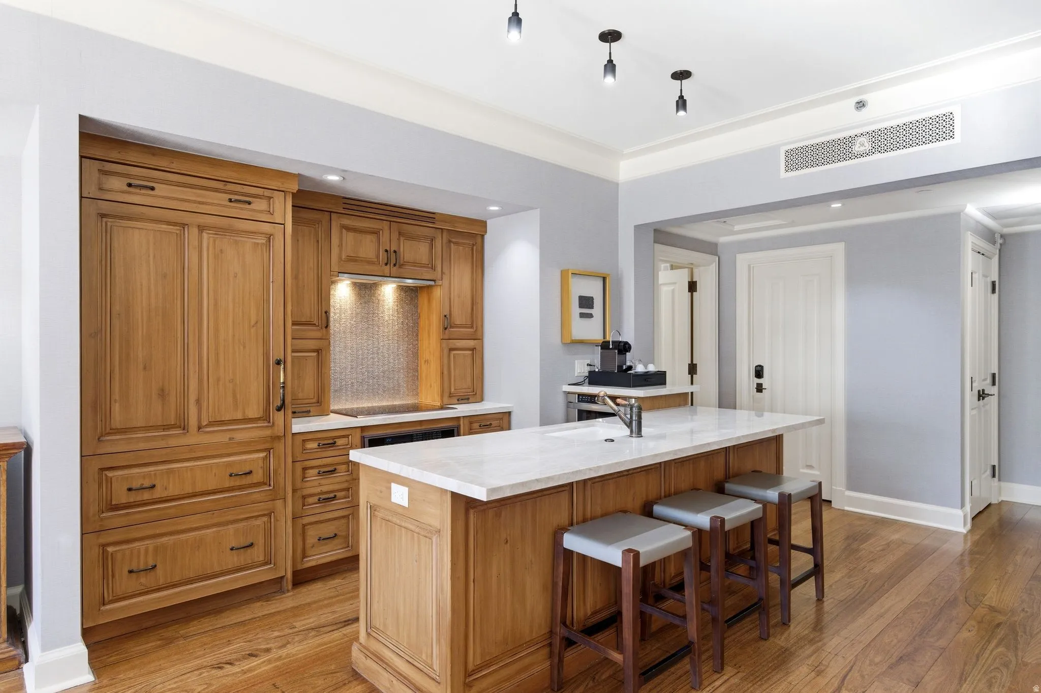 Kitchen featuring wood-finish cabinetry, a built-in refrigerator, and a kitchen island with seating