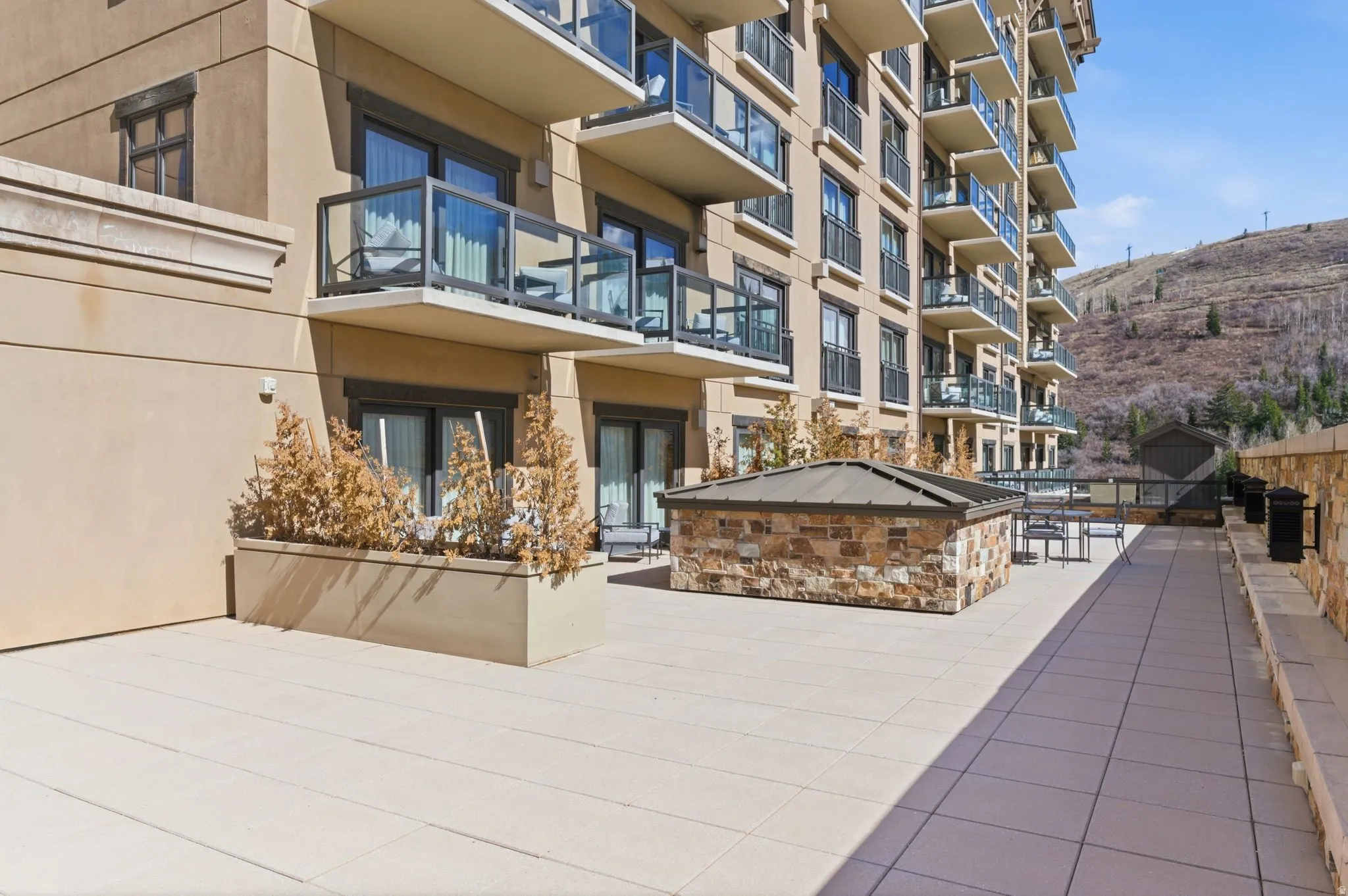 Spacious outdoor patio with stone-veneer accent wall and large format tile flooring