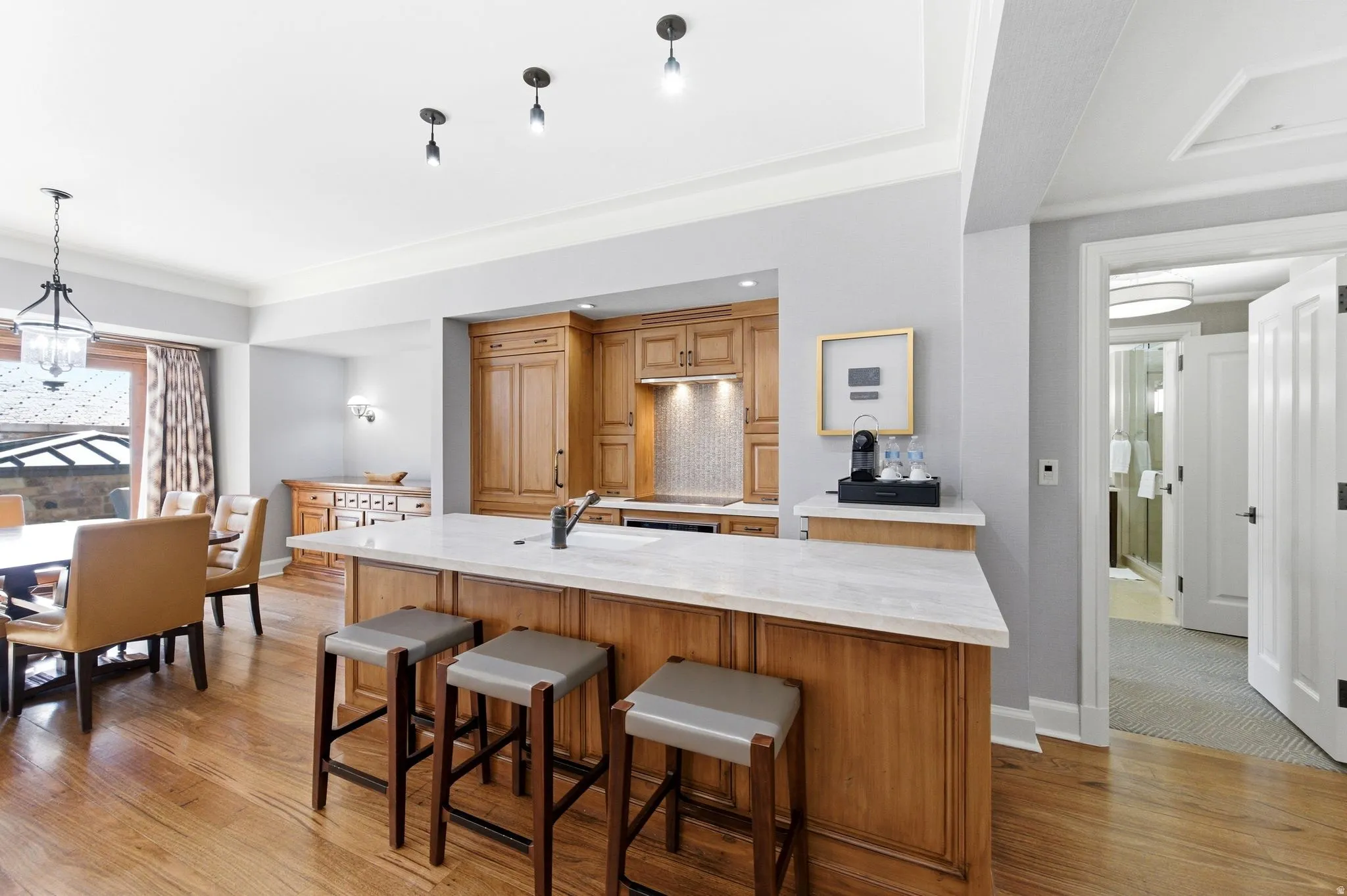 Open-concept kitchen featuring wood cabinetry, white stone countertops, and a tiled backsplash