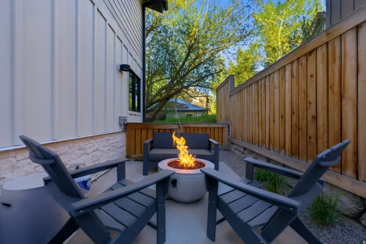 Private patio featuring a built-in fire pit, concrete flooring, stone veneer detailing, and wood fencing