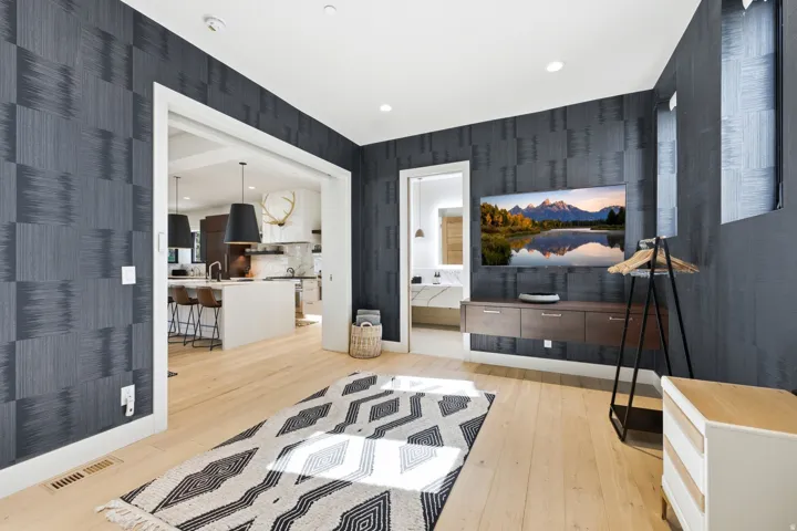 Spacious interior room featuring light wood-finish flooring and patterned wall covering