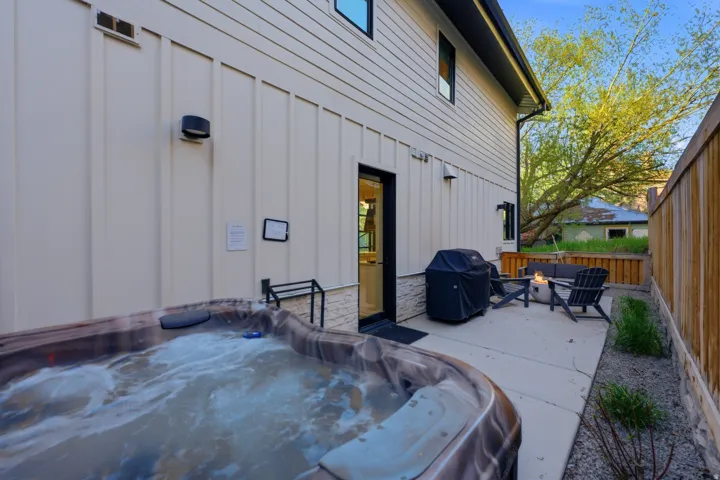 Outdoor patio featuring a hot tub, concrete paving, and a wooden privacy fence