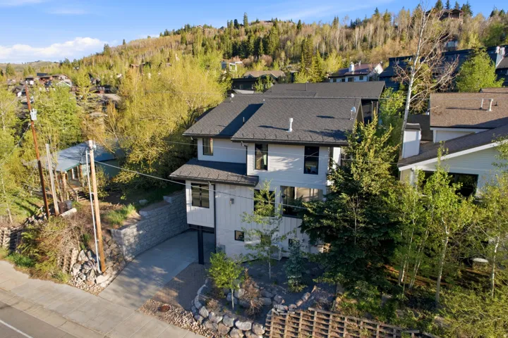 Multi-story home featuring a gray shingle roof, light-toned siding, and dark-framed windows