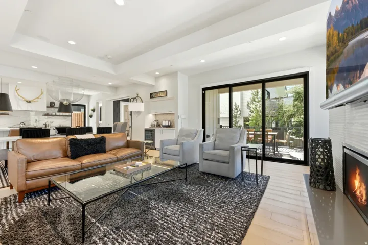 Open-concept living space featuring light wood-finish flooring, a recessed lighting scheme, and a contemporary linear fireplace