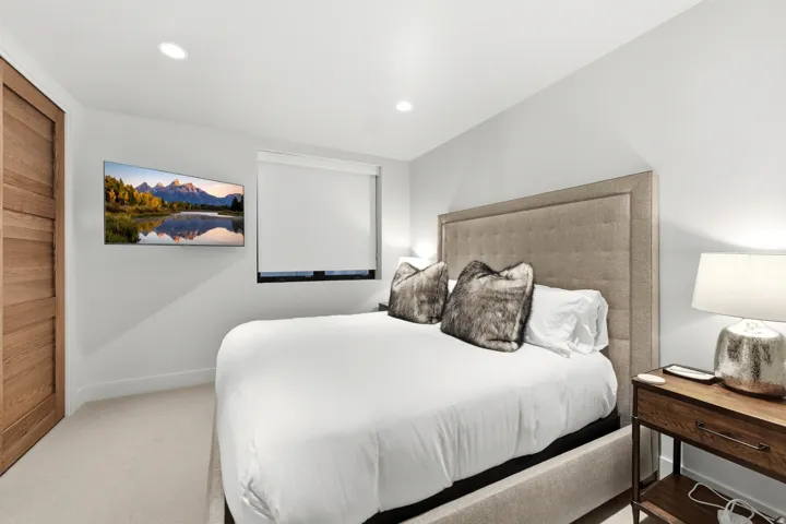 Bedroom featuring recessed lighting, light-toned carpeting, a window with roller shades, and a wall-mounted flat-screen television