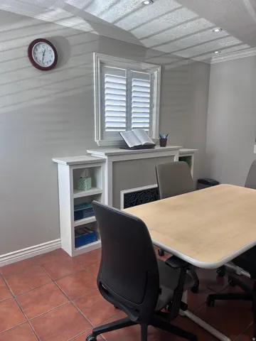 Room featuring terracotta-style floor tiles, a built-in window structure with plantation shutters, integrated shelving, and recessed ceiling lighting