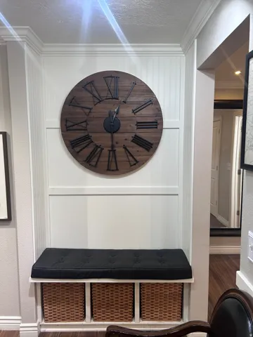 Built-in bench seating with cubby storage, wainscoting paneling, crown molding, and wood-finish flooring