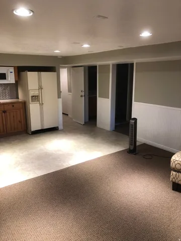 Open concept living area with recessed lighting, two-tone walls, and a combination of carpet and tile flooring