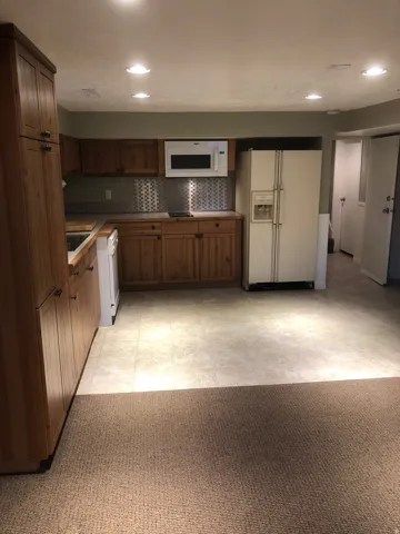 Functional kitchen space featuring wood-finish cabinetry, a metal tile backsplash, and recessed lighting