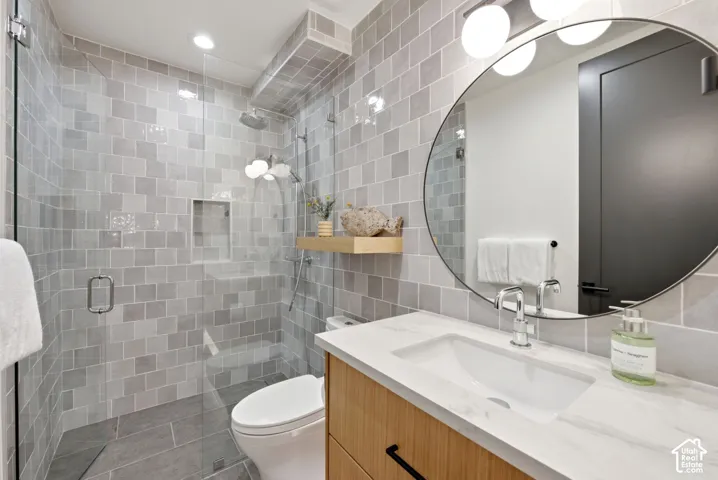 Contemporary bathroom featuring a glass-enclosed shower with square wall tiling and a recessed niche