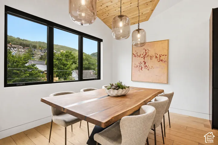 Expansive black-framed windows overlooking a mountainous landscape, complemented by a wood-plank ceiling