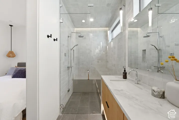 Contemporary bathroom with glass-enclosed shower featuring a rain showerhead and handheld sprayer, textured wall tiles, and recessed lighting