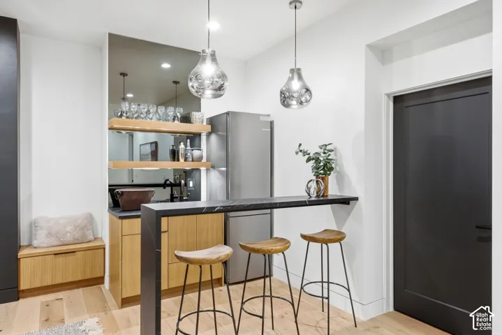 Built-in wet bar featuring a dark countertop, undermount sink, and open wood shelving