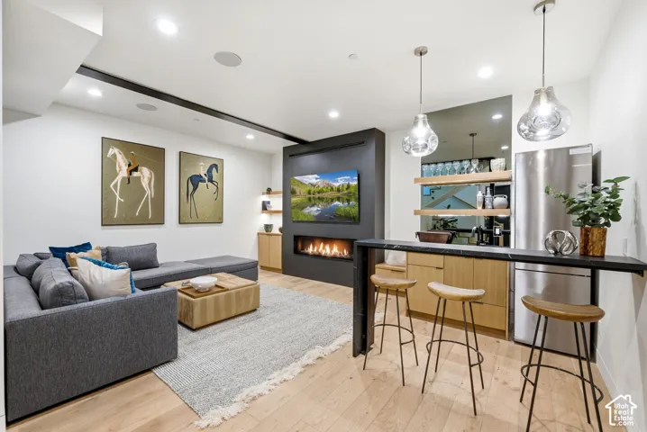 Integrated living space featuring wood-finish flooring, a linear fireplace, and a built-in wet bar with a dark countertop