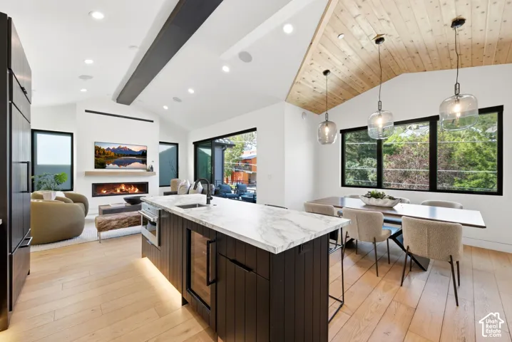 Open-concept living space featuring light wood-finish flooring and a vaulted wood-paneled ceiling
