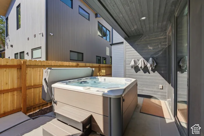 Private outdoor patio featuring a hot tub, concrete paving, and a wood privacy fence
