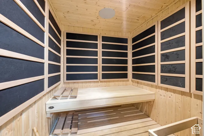 Sauna interior featuring wood-paneled walls and ceiling, built-in wooden benches, and wall-mounted heating elements