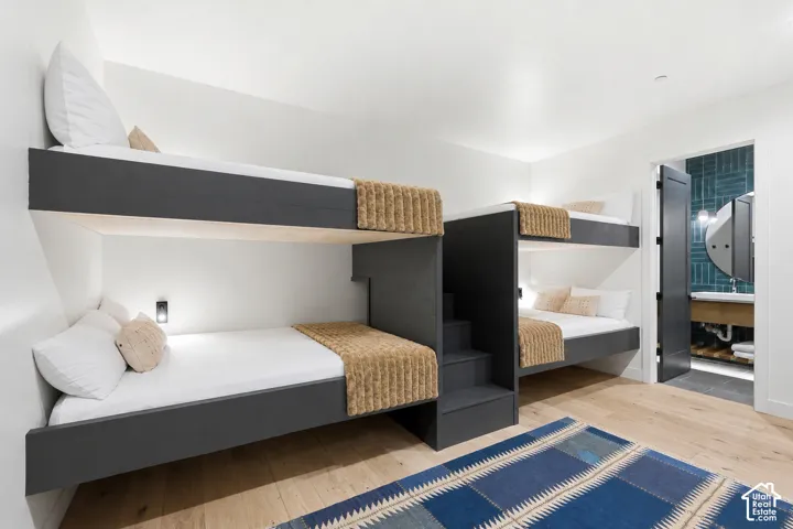 Contemporary bunk room featuring two built-in bunk bed structures with integrated steps and wall-mounted lighting