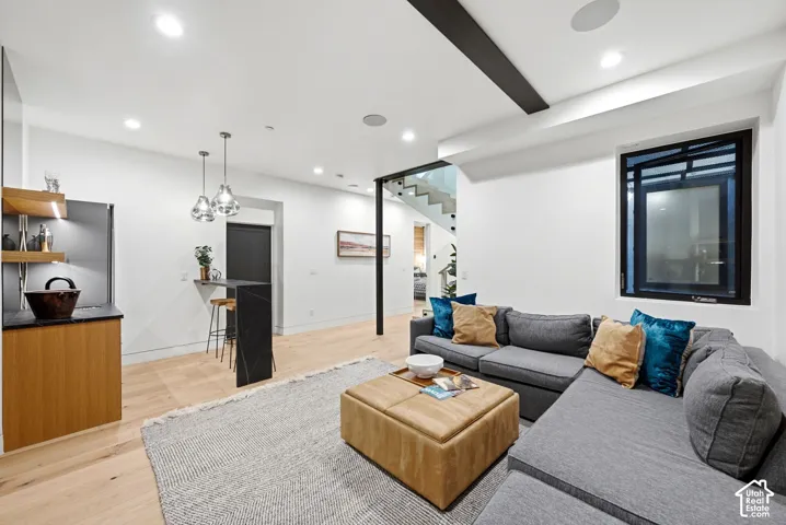 Open-concept living area featuring light wood-finish flooring, recessed lighting, and a built-in wet bar with wood cabinetry and open shelving
