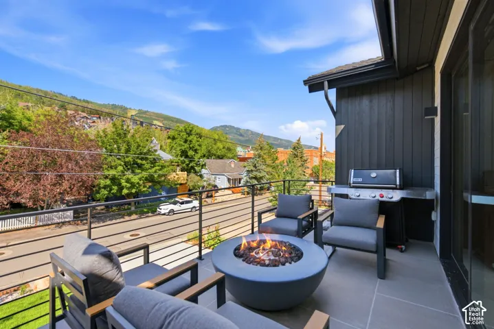 Spacious outdoor patio featuring slate-gray tile flooring, a built-in outdoor grill, and a modern fire pit