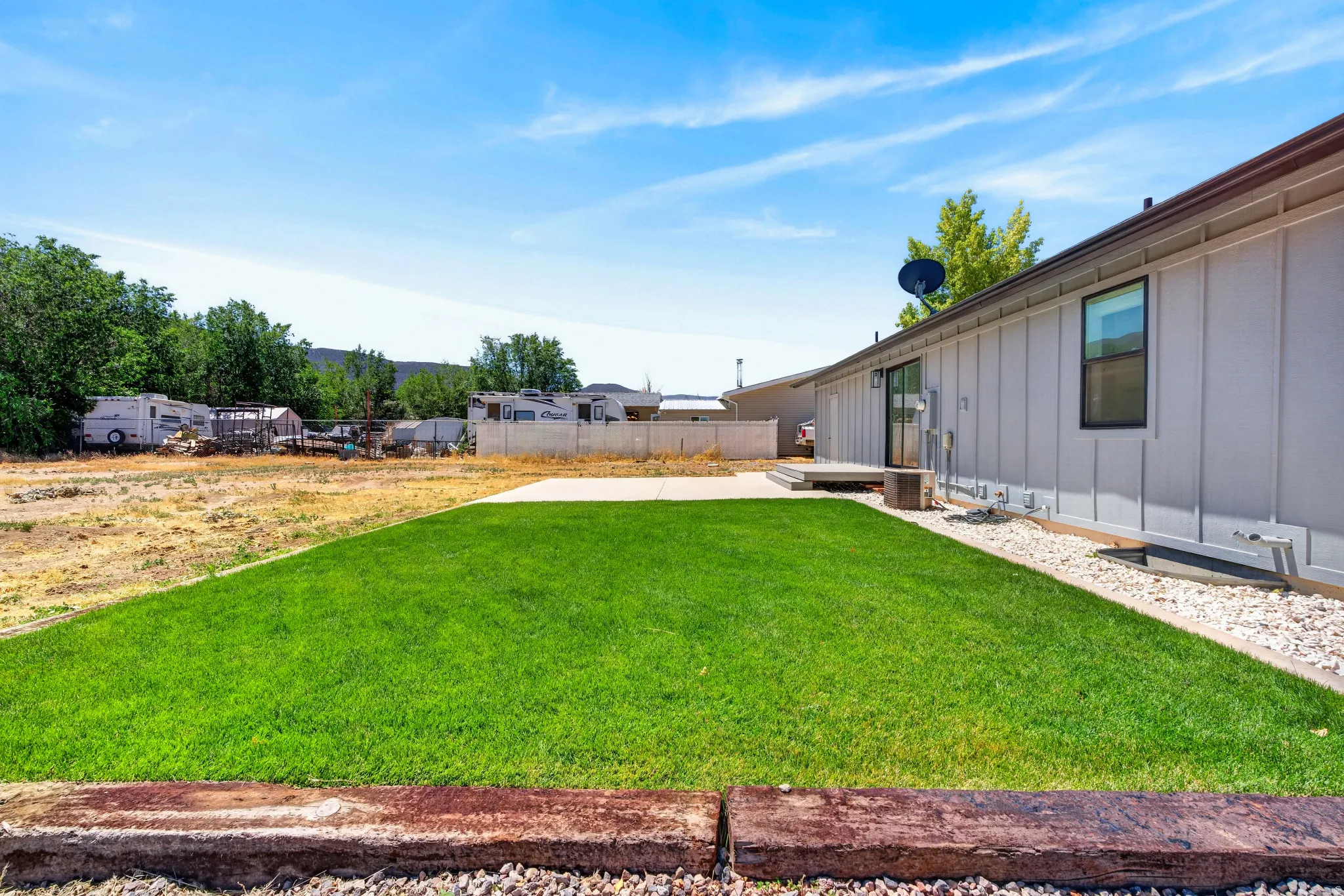 Expansive green lawn with a concrete patio