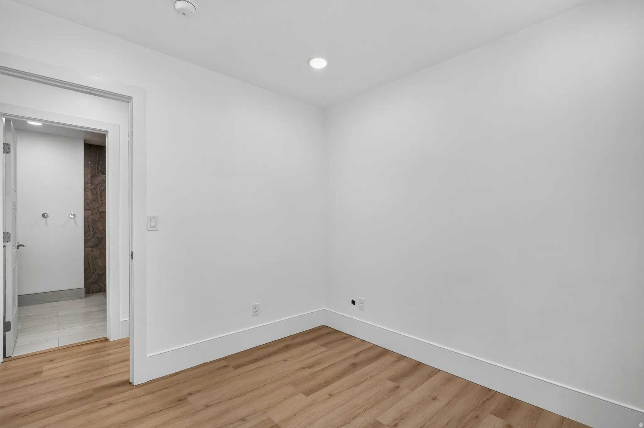 Room with wood-finish flooring, white baseboards, and recessed lighting