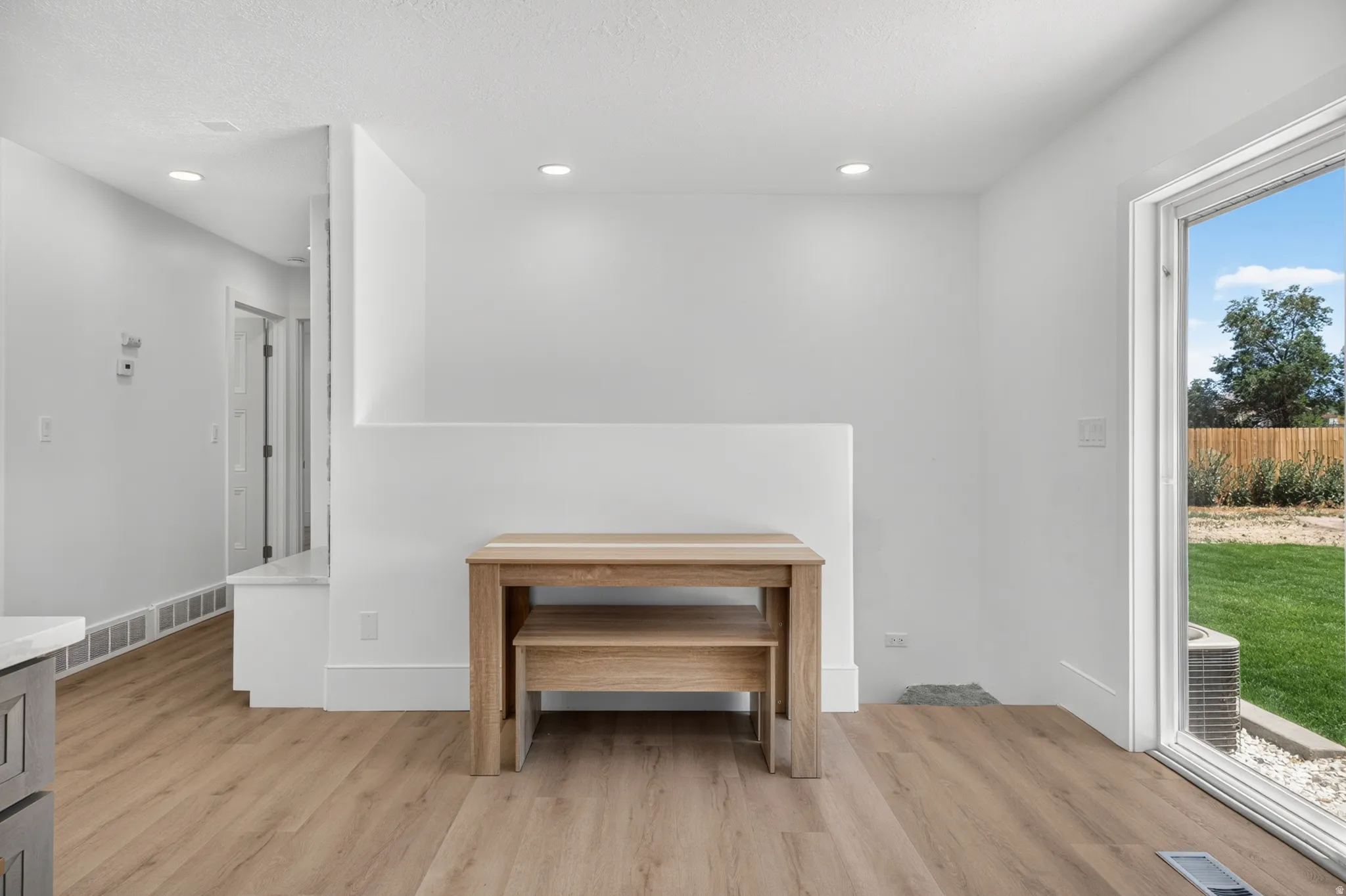 Bright interior space featuring wood-finish flooring, recessed ceiling lighting, and a white half-wall partition