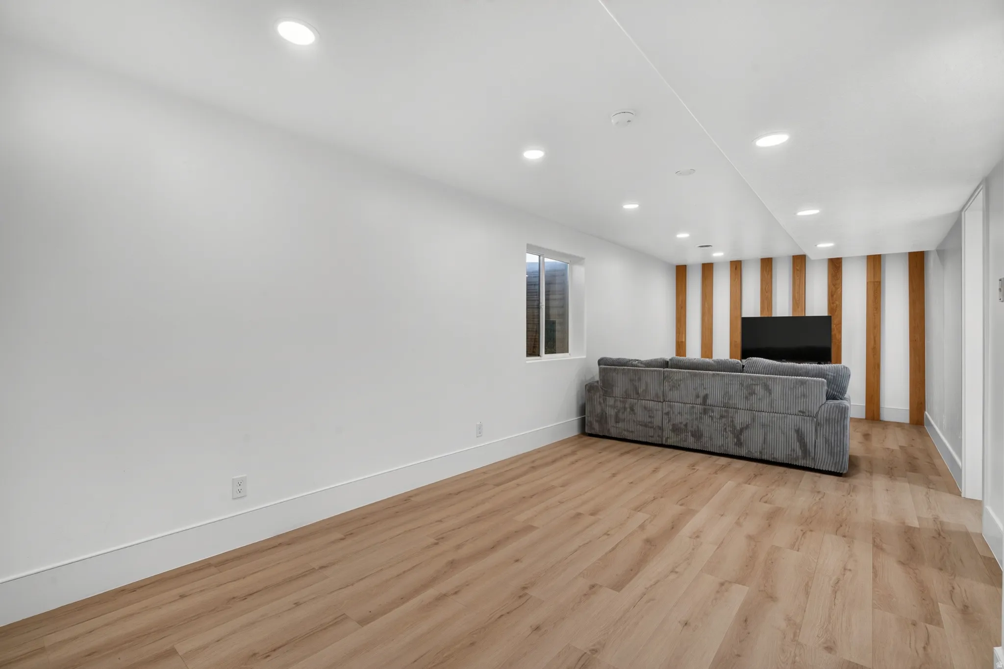 Spacious room featuring wood-finish flooring, recessed lighting, and a window providing natural light