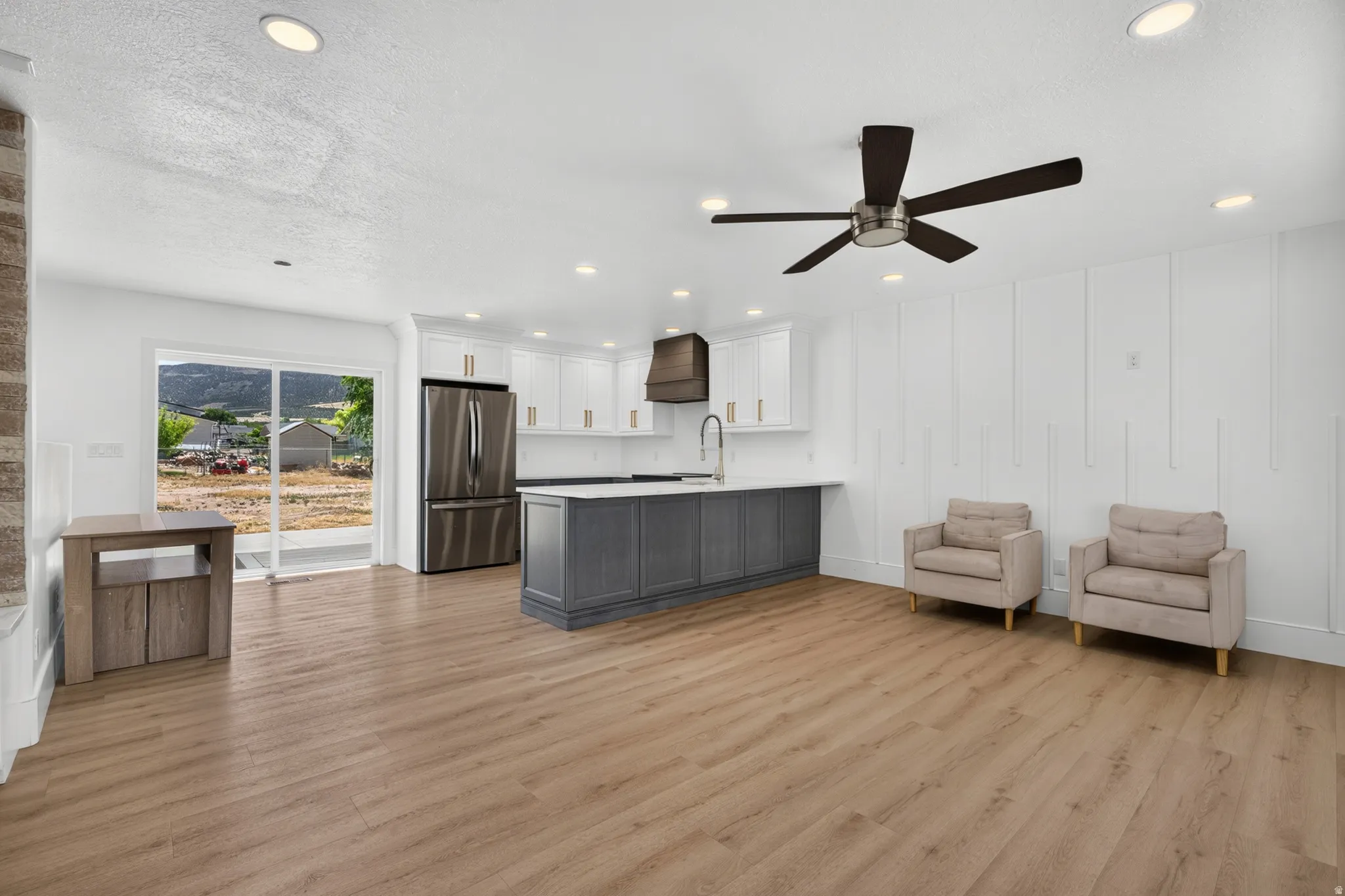 Open-concept living area with wood-finish flooring, recessed lighting, and a contemporary ceiling fan