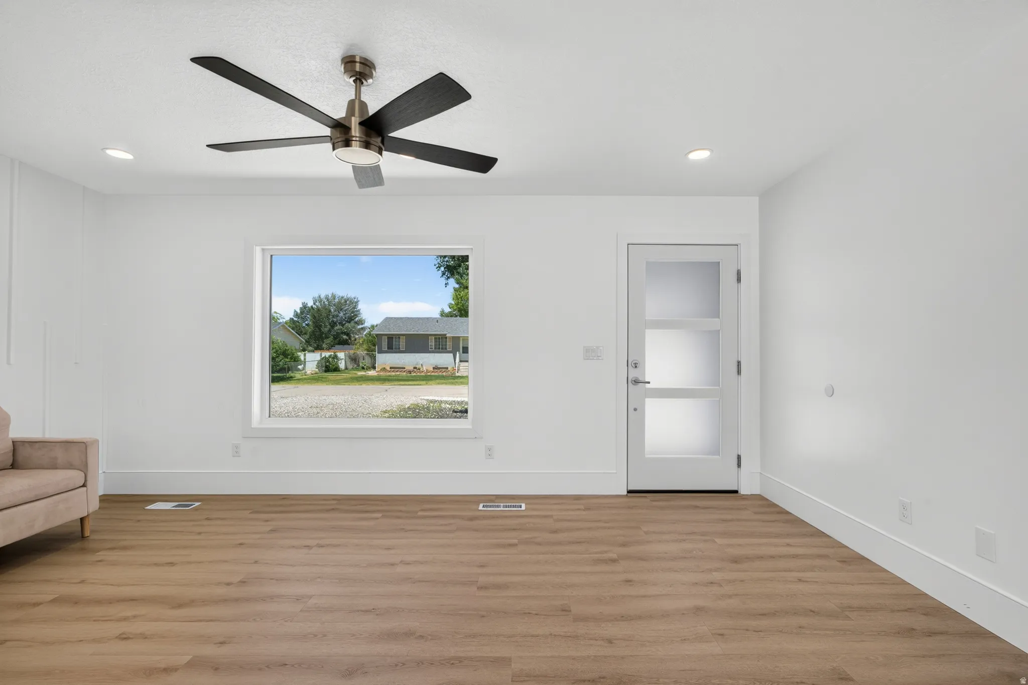 Spacious living area featuring wood-finish flooring, recessed lighting, and a modern ceiling fan
